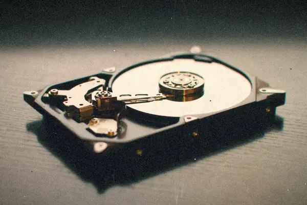 An opened hard disk drive showing its platter on a dark surface.