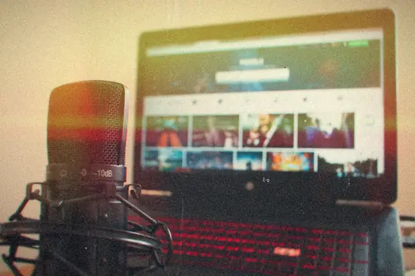A studio microphone in front of a laptop showing a video site.