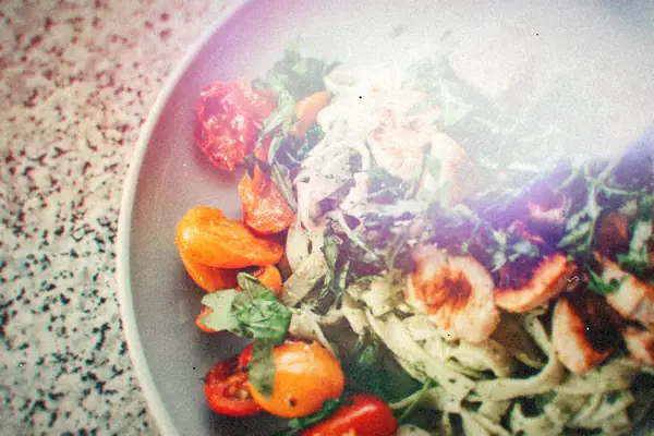Pesto pasta topped with seared chicken, arugula and roasted cherry tomatoes.