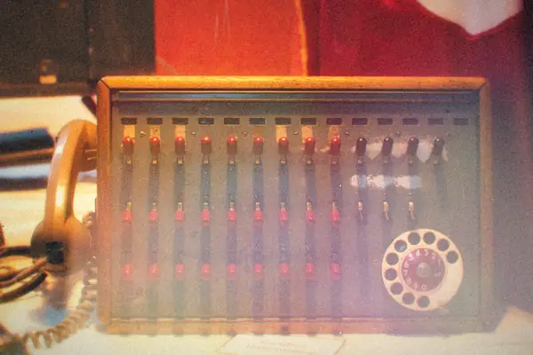 A vintage telephone switchboard with toggle switches and a rotary dial.