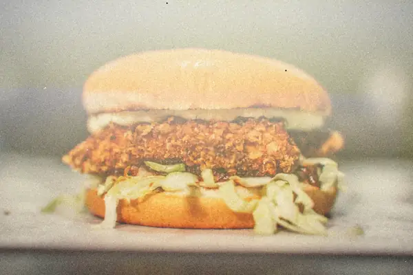 A crispy breaded chicken sandwich with shredded lettuce and mayo on a soft bun.