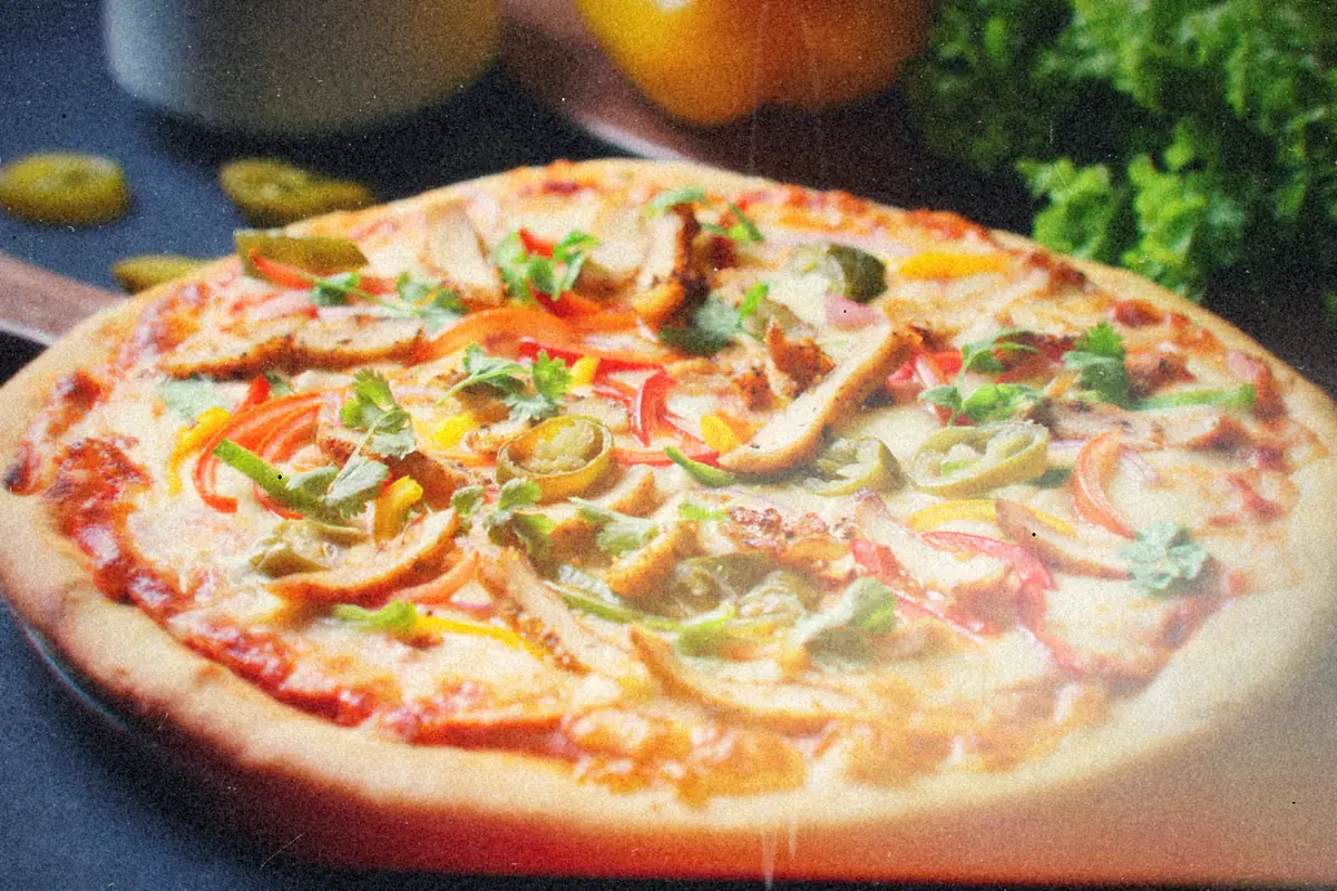A chicken pizza topped with sliced peppers, jalapenos and fresh cilantro.