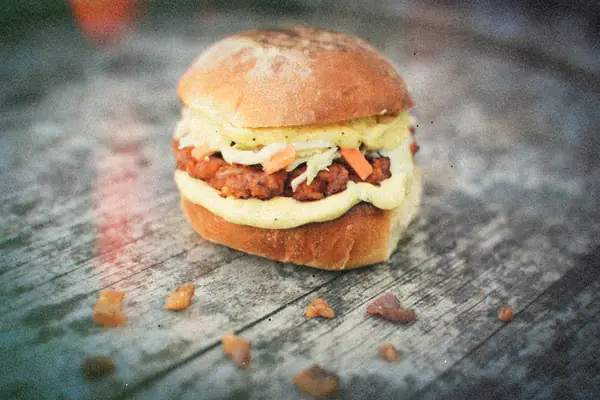 A sloppy joe sandwich with saucy ground beef, slaw and creamy sauce on a soft bun.
