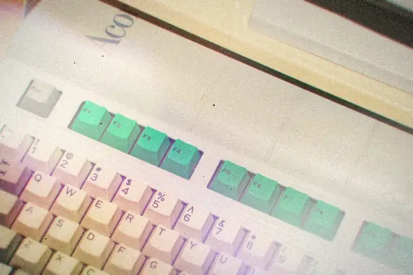 Close-up of a worn vintage computer keyboard with green function keys.