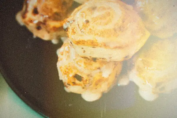 Glazed cinnamon rolls piled on a plate.