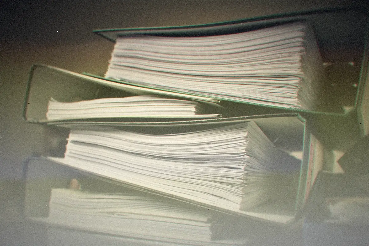 A stack of overstuffed ring binders full of paper.