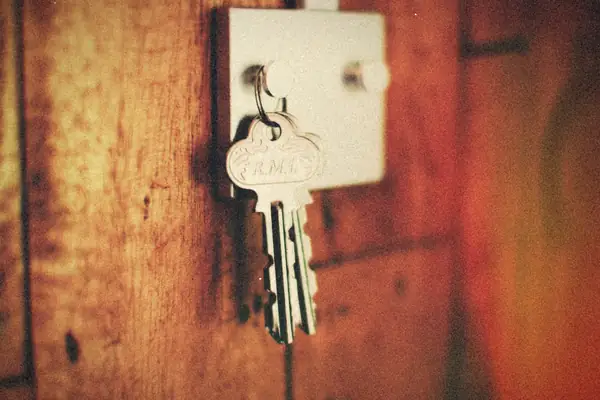 A ring of keys hanging from a hook on a red wooden wall.