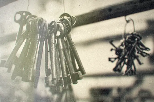 Big rings of old iron skeleton keys hanging from hooks, in black and white.