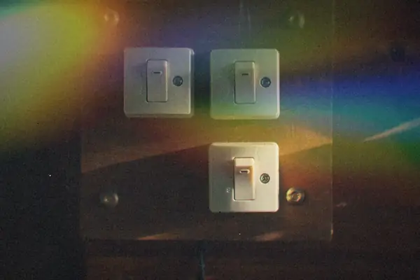 Old light switches mounted on a wooden panel in a dark room.