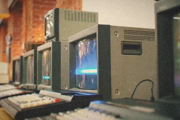 A row of vintage CRT computer terminals lined up on a desk.