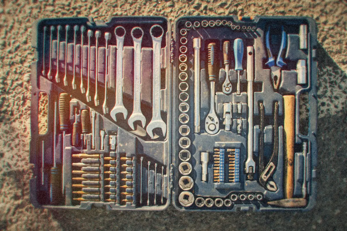 An open toolbox with rows of wrenches, sockets and screwdrivers, seen from above.