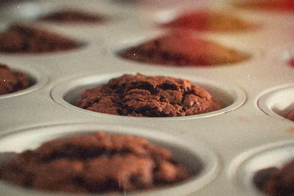 Chocolate muffins cooling in a metal muffin pan.