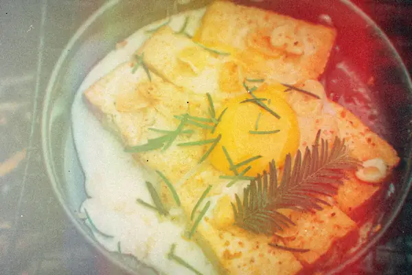 Griddled toast with a fried egg and a rosemary sprig in a frying pan.