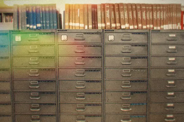 Banks of gray steel file drawers beneath shelves of bound books.