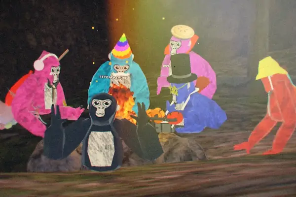 A group of colorful Gorilla Tag players in party hats gathered around a campfire.