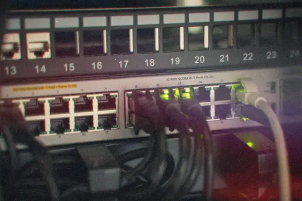 Network cables plugged into a patch panel and switch with green status lights.