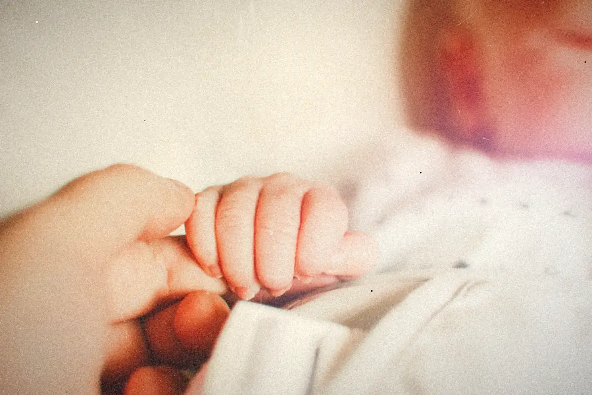 A baby's hand holding an adult's finger.