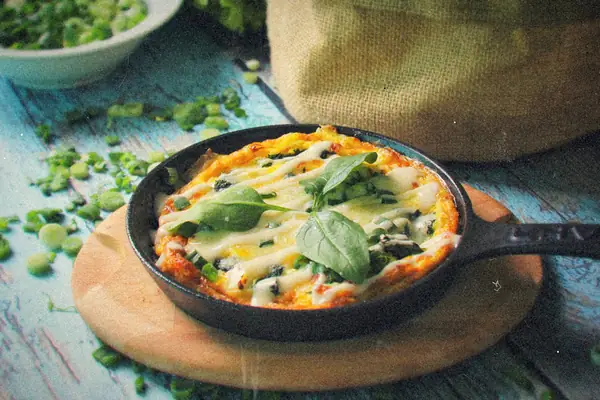 An egg and spinach frittata with melted cheese in a small cast iron skillet.