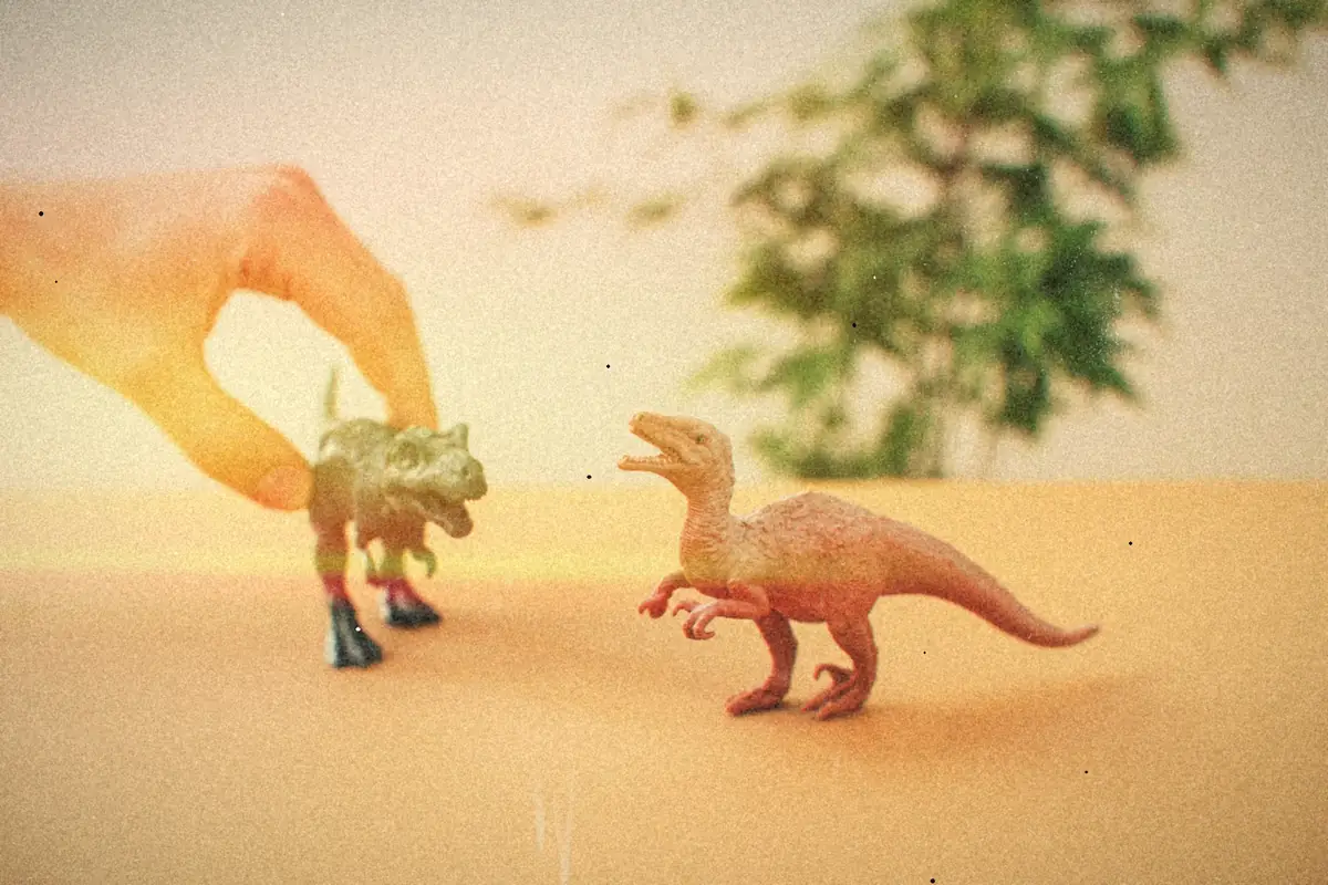 Hands playing with toy dinosaur figures.