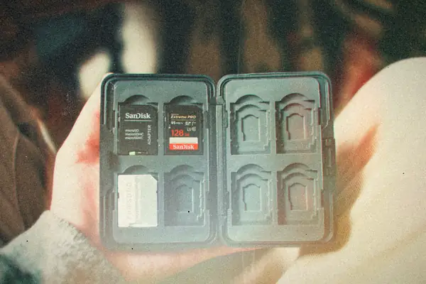 A hand holding an open memory card case with a microSD adapter and SD cards slotted inside.