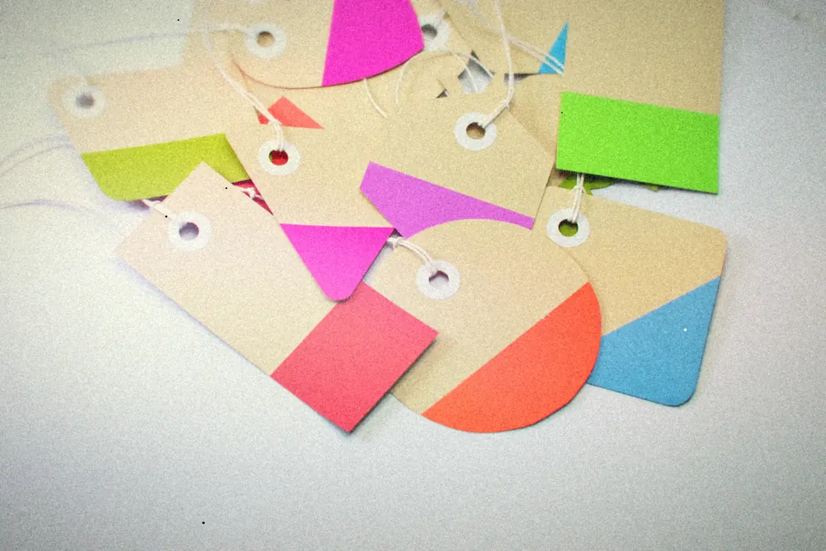 Paper tags with bright pink, green, orange and blue color blocks, tied with string.