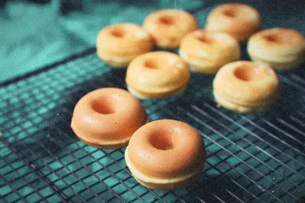 Rows of plain golden mini donuts cooling on a wire rack.