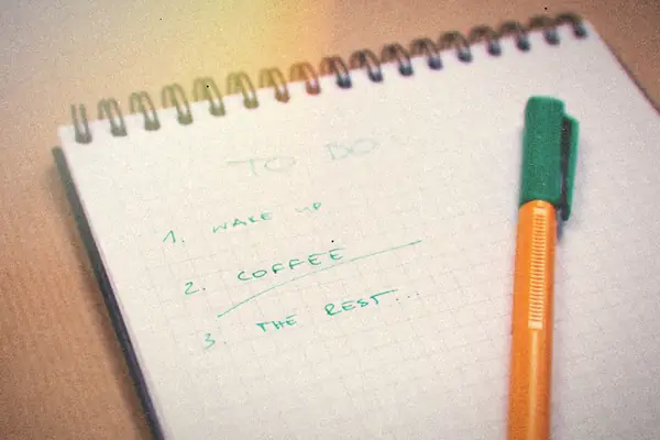 A handwritten to-do list on a graph-paper notebook with an orange pen.