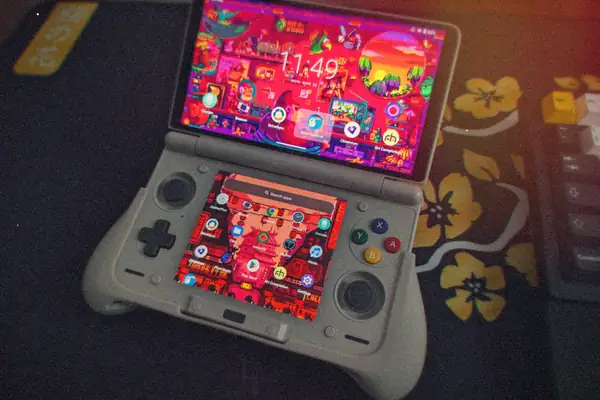 An AYN Thor dual-screen handheld opened on a desk, both screens lit up with Android home screens.
