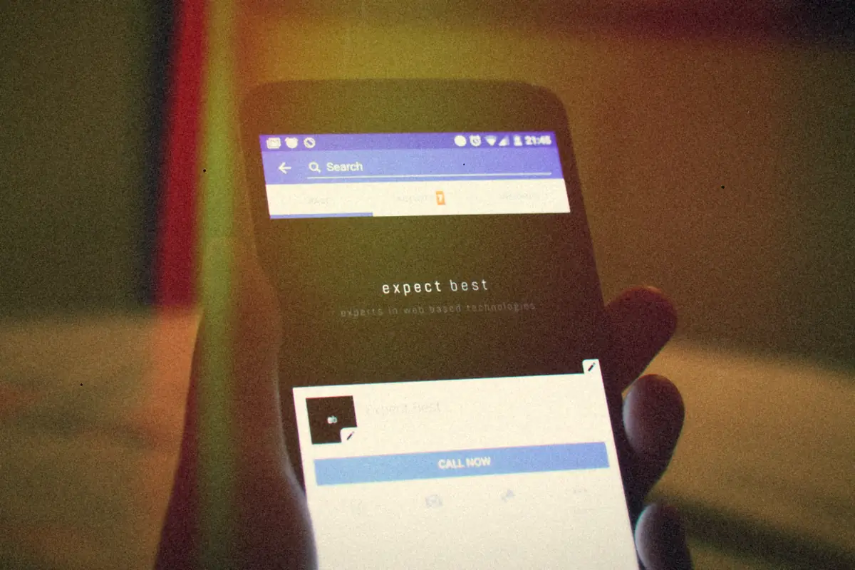 A hand holding a phone with a social media app open.