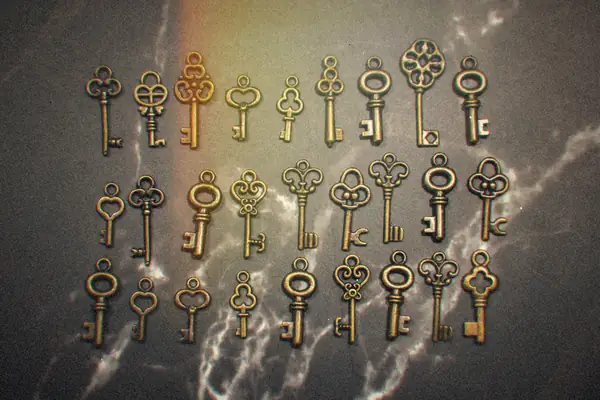 Rows of matching antique skeleton keys laid out on a marble surface.