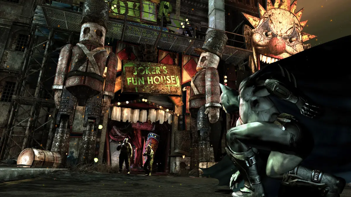 Batman crouched on a rooftop outside a garish carnival-style building on a rainy Arkham City street at night.