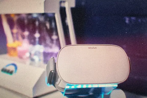 A white Oculus VR headset sitting on a stand under cool blue light.