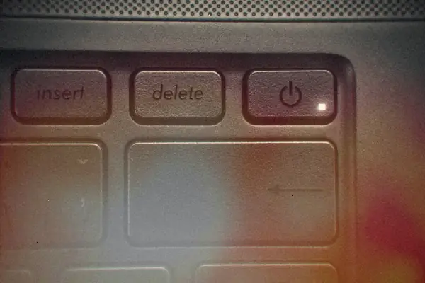 A close-up of a laptop keyboard's power button with its small status light on.