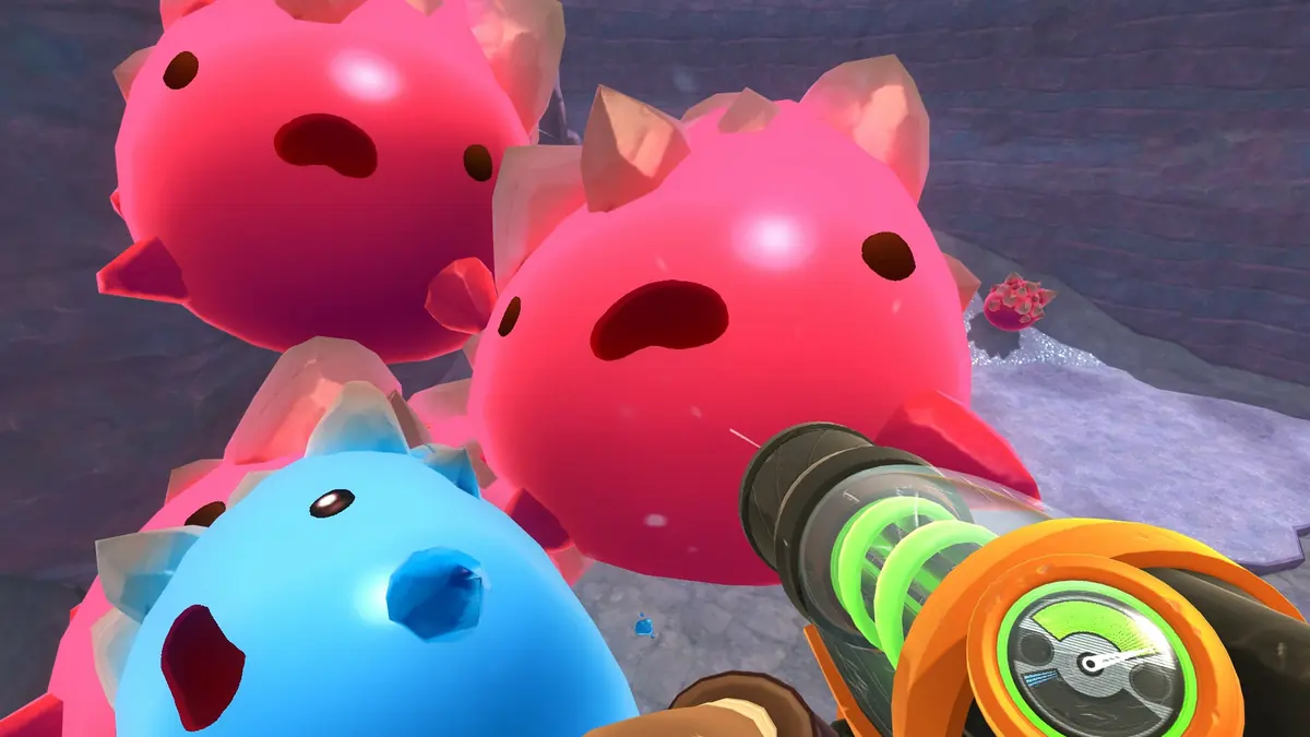 Beatrix pointing her vacpack at a cluster of pink and blue spiky slimes.