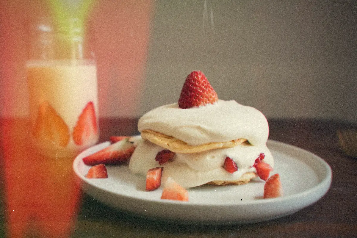 A strawberry shortcake layered with whipped cream and fresh strawberries on a white plate.