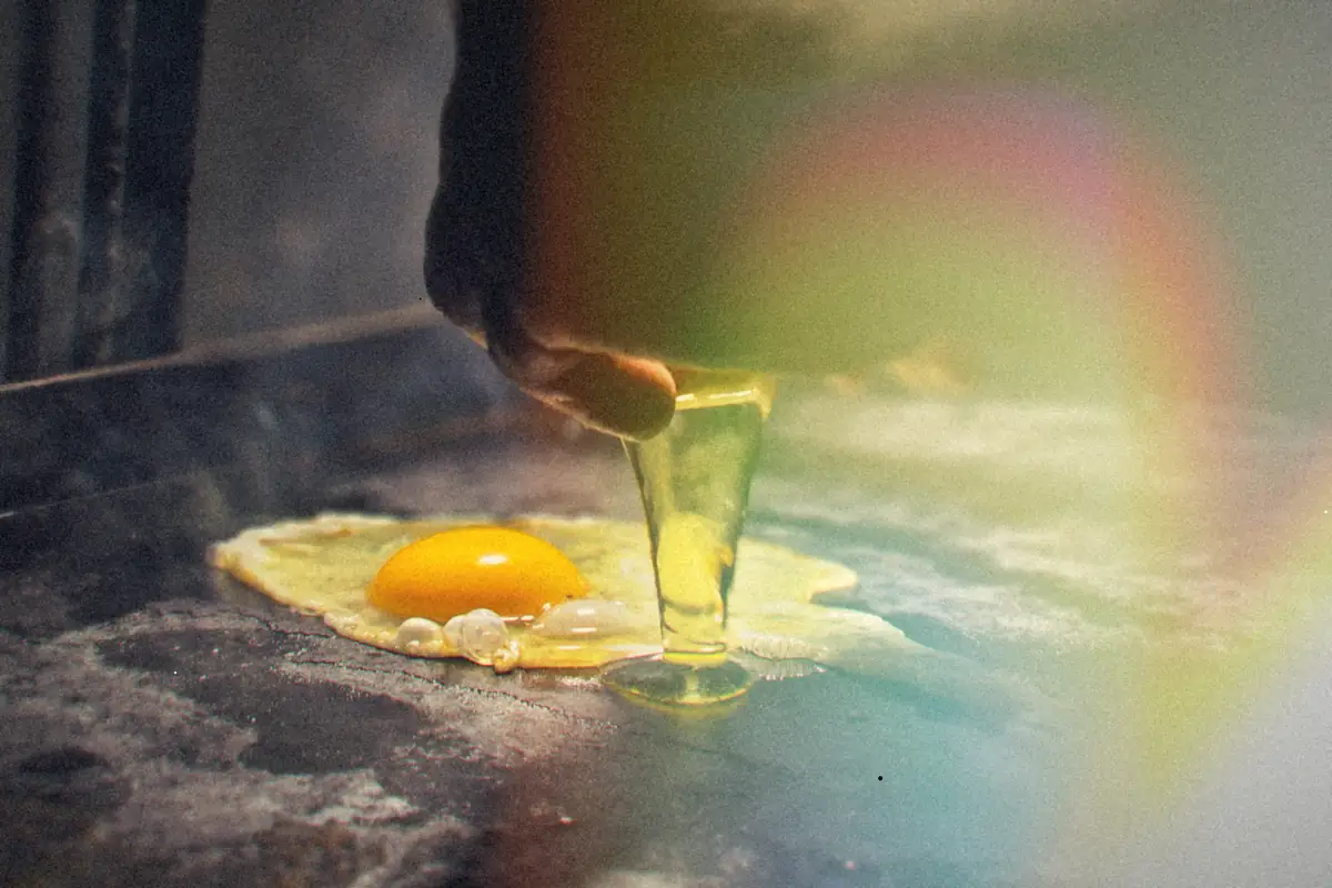 An egg being cracked onto a hot, seasoned griddle.