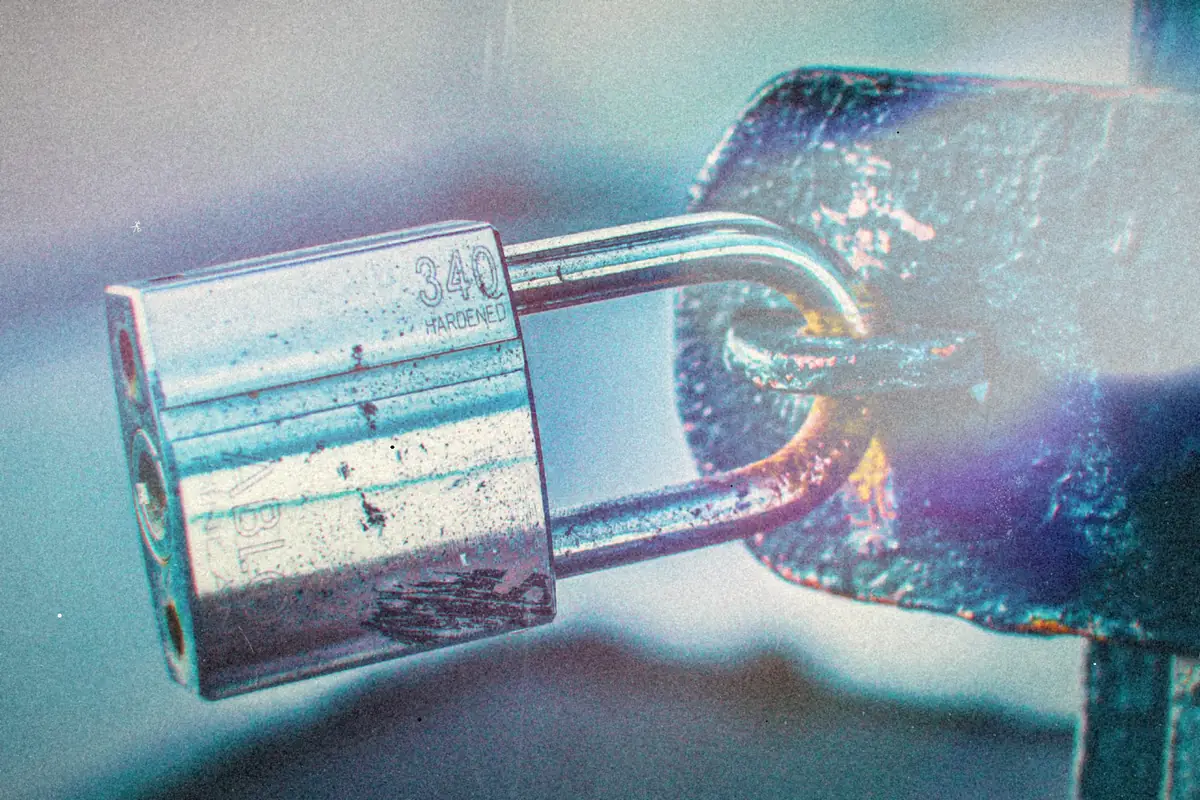A heavy steel padlock hanging on a rusty metal gate.