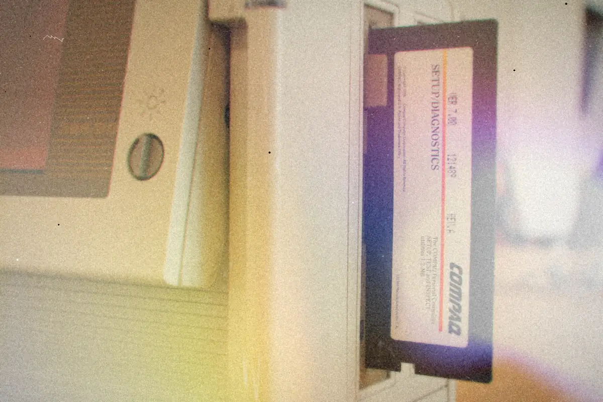 A floppy disk sticking out of the drive slot of an old beige computer.