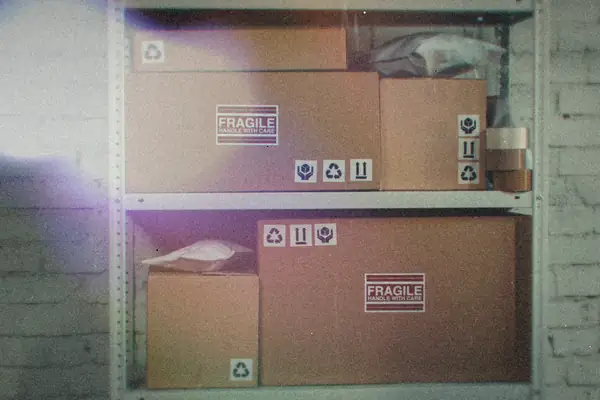 Taped cardboard shipping boxes stacked on a metal storage rack.