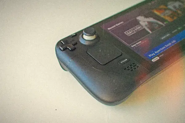 A Steam Deck handheld on a white surface with the Steam library of recent games on its screen.